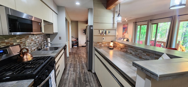 3400 Lakeside Dr S Unit 17, Petoskey, MI 49770 - kitchen with stainless steel appliances, dark wood-style floors, decorative backsplash, white cabinets, and decorative light fixtures