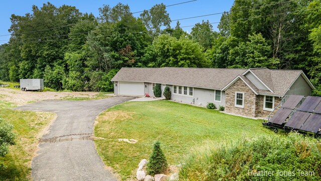 8035 Jericho Ave NE, Rockford, MI 49341 - view of front of house featuring stone siding, driveway, a garage, a front lawn, and roof with shingles