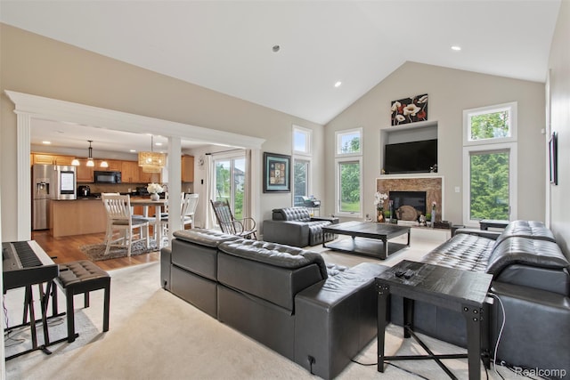 7759 W Branch Ct, Ypsilanti, MI 48197 - living area featuring high vaulted ceiling, light wood-type flooring, a glass covered fireplace, recessed lighting, and a chandelier