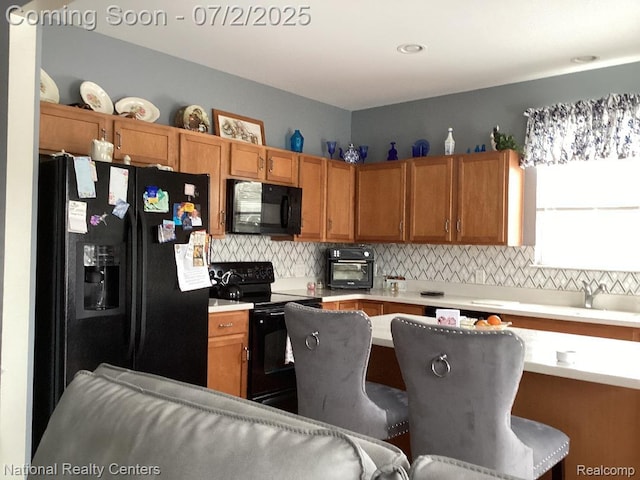 636 Zion Ct S, Howell, MI 48843 - kitchen with black appliances, light countertops, backsplash, brown cabinets, and a kitchen bar