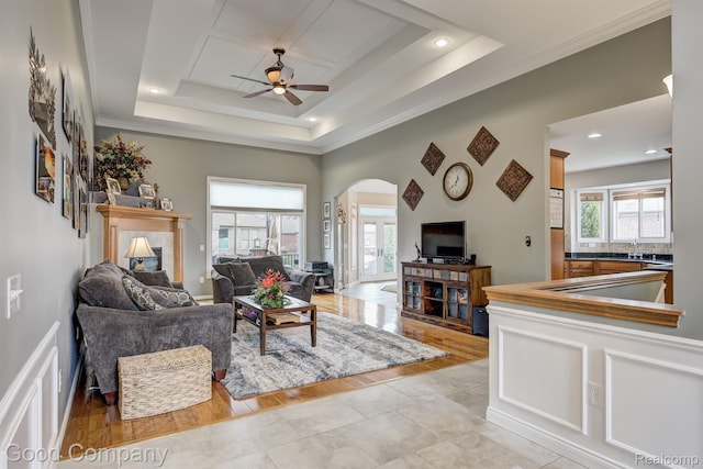 63705 Monticello E, Washington, MI 48095 - living area featuring a ceiling fan, arched walkways, a fireplace, a tray ceiling, and crown molding
