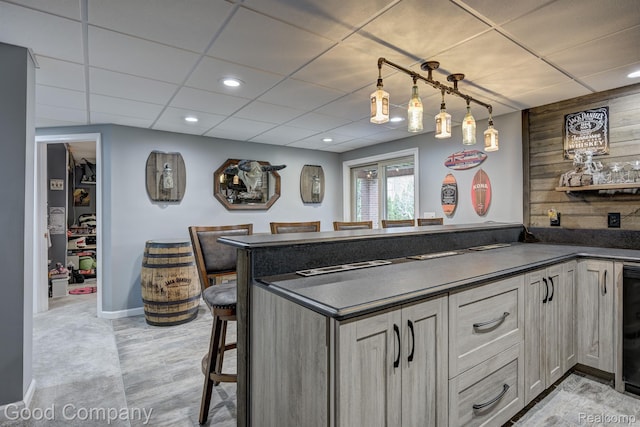 63705 Monticello E, Washington, MI 48095 - kitchen with dark countertops, a paneled ceiling, light wood-style flooring, a breakfast bar, and a peninsula