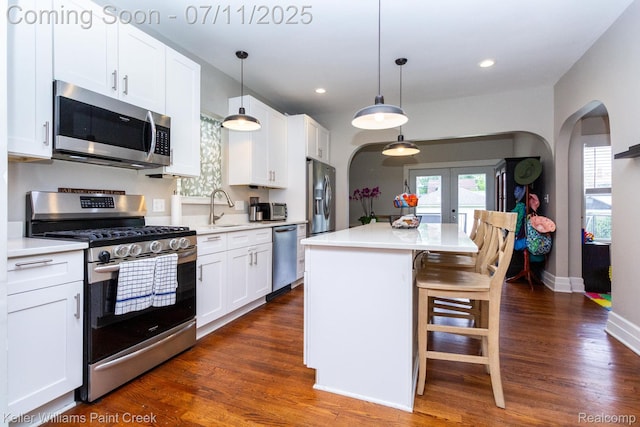 1424 Lakepointe St, Detroit, MI 48230 - kitchen with appliances with stainless steel finishes, arched walkways, a breakfast bar, white cabinets, and dark wood finished floors