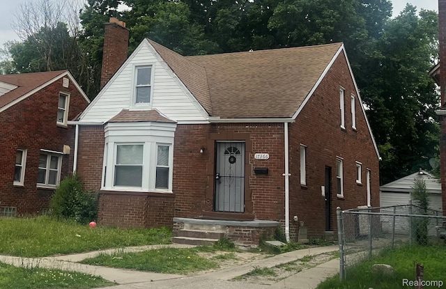 17366 Mansfield St, Detroit, MI 48235 - view of front of house featuring a shingled roof, brick siding, and a chimney
