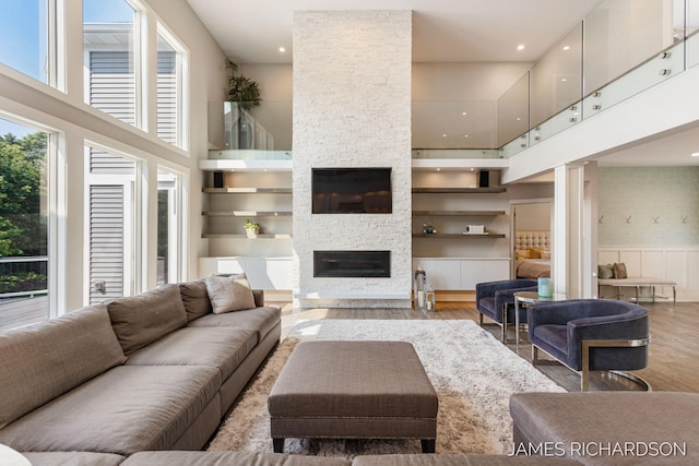 12974 Boulderway Trl, Grand Haven, MI 49417 - living area with a high ceiling, wood finished floors, a stone fireplace, a wainscoted wall, and recessed lighting