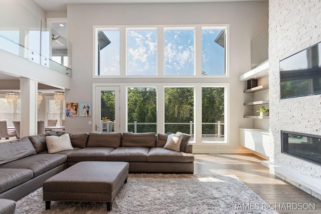 12974 Boulderway Trl, Grand Haven, MI 49417 - living room with a towering ceiling, healthy amount of natural light, wood finished floors, a fireplace, and built in features