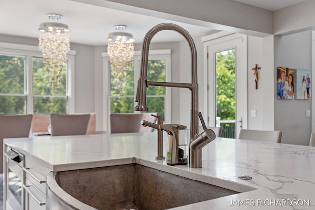 12974 Boulderway Trl, Grand Haven, MI 49417 - kitchen with a chandelier, white cabinets, and light stone countertops