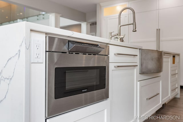 12974 Boulderway Trl, Grand Haven, MI 49417 - kitchen view of oven, white cabinets, wood finished floors, and light stone countertops