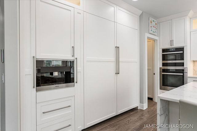 12974 Boulderway Trl, Grand Haven, MI 49417 - kitchen with double oven, dark wood-type flooring, white cabinetry, light stone counters, and glass insert cabinets