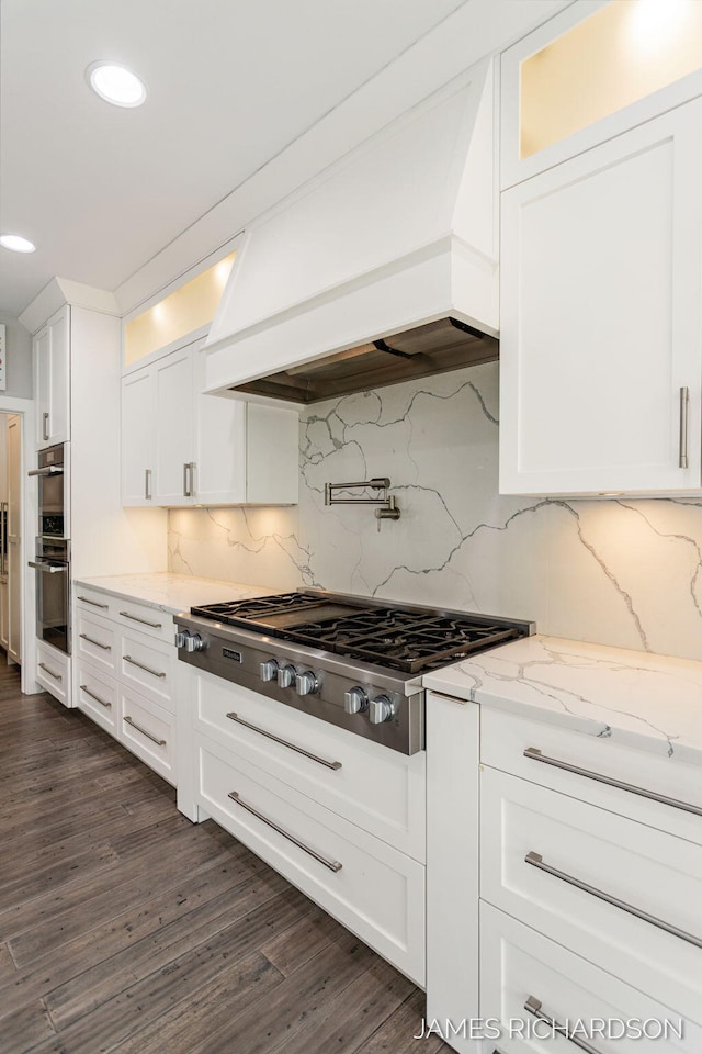 12974 Boulderway Trl, Grand Haven, MI 49417 - kitchen featuring appliances with stainless steel finishes, custom exhaust hood, white cabinets, glass insert cabinets, and recessed lighting