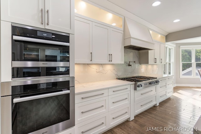 12974 Boulderway Trl, Grand Haven, MI 49417 - kitchen with appliances with stainless steel finishes, white cabinetry, custom range hood, backsplash, and recessed lighting