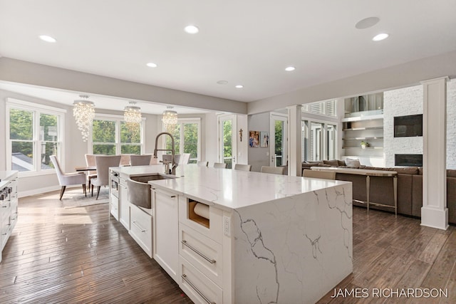 12974 Boulderway Trl, Grand Haven, MI 49417 - kitchen with dark wood-style flooring, white cabinets, a fireplace, recessed lighting, and an island with sink
