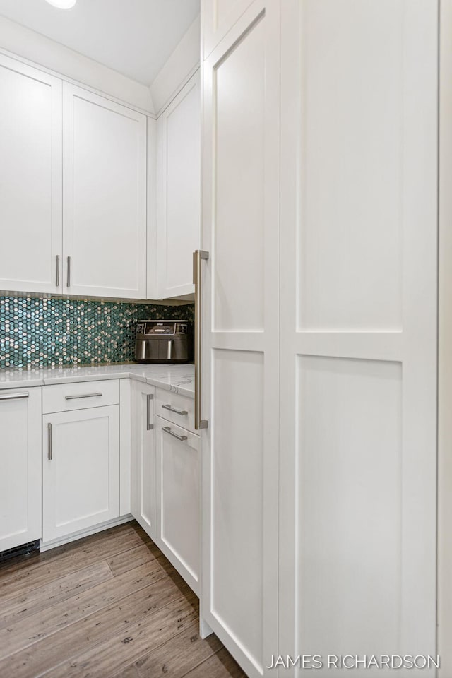 12974 Boulderway Trl, Grand Haven, MI 49417 - kitchen featuring white cabinets, backsplash, light wood-style floors, and light stone countertops