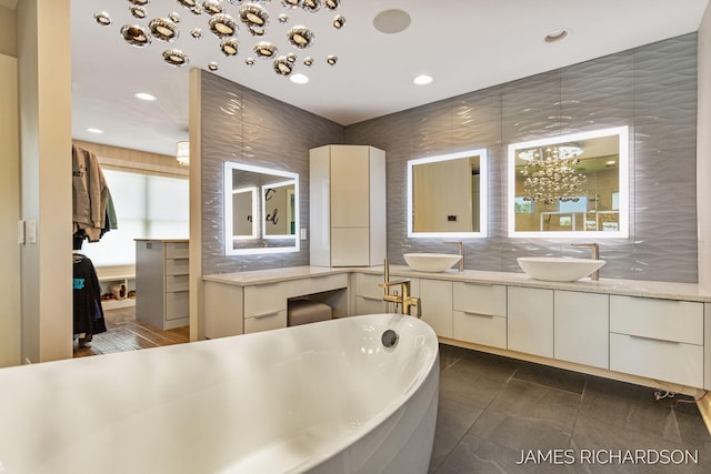 12974 Boulderway Trl, Grand Haven, MI 49417 - bathroom featuring a soaking tub, double vanity, recessed lighting, decorative backsplash, and tile patterned flooring