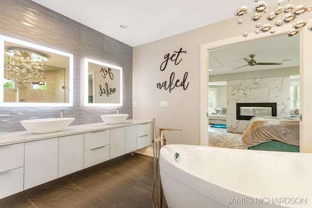 12974 Boulderway Trl, Grand Haven, MI 49417 - ensuite bathroom with double vanity, a soaking tub, a ceiling fan, a fireplace, and a chandelier