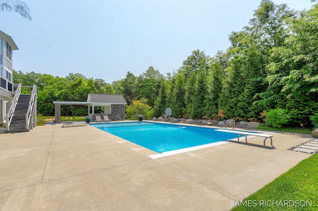 12974 Boulderway Trl, Grand Haven, MI 49417 - swimming pool with a storage structure, stairs, a patio area, an outdoor structure, and a diving board
