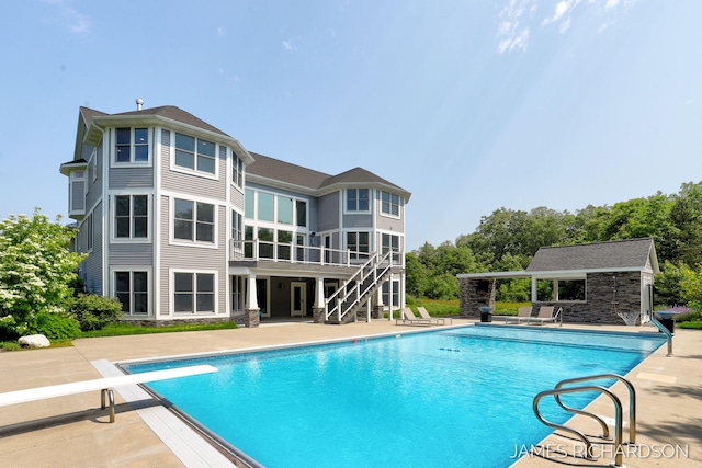 12974 Boulderway Trl, Grand Haven, MI 49417 - swimming pool featuring a patio, stairs, a diving board, an outbuilding, and a wooden deck