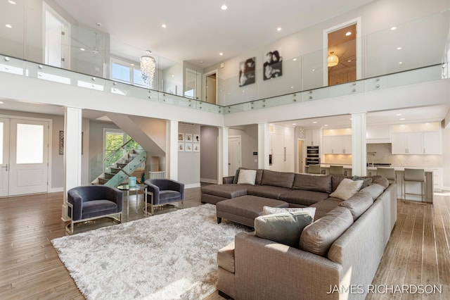 12974 Boulderway Trl, Grand Haven, MI 49417 - living room with ornate columns, a high ceiling, light wood-type flooring, stairway, and recessed lighting