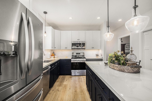 765 S Haven Pl, South Haven, MI 49090 - kitchen with stainless steel appliances, dark cabinets, light countertops, white cabinetry, and light wood-type flooring