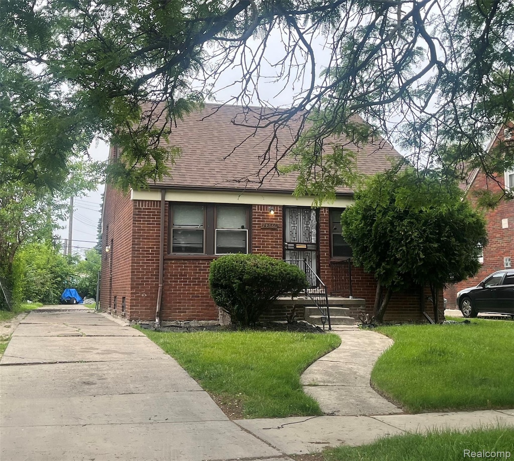 14561 Prevost St, Detroit, MI 48227 - view of front of home with brick siding, a shingled roof, and a front yard