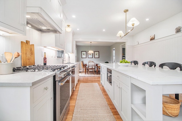 5145 Hensley Dr, Ann Arbor, MI 48103 - kitchen featuring appliances with stainless steel finishes, premium range hood, light wood-style flooring, light countertops, and recessed lighting