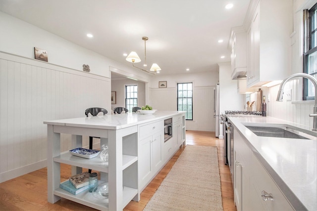 5145 Hensley Dr, Ann Arbor, MI 48103 - kitchen with white cabinets, light wood-style floors, stainless steel microwave, open shelves, and a center island