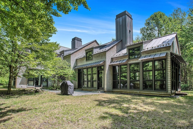 7085 Youngren Rd, Three Oaks, MI 49128 - rear view of house featuring a standing seam roof, a chimney, a metal roof, a yard, and a patio area