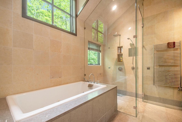 7085 Youngren Rd, Three Oaks, MI 49128 - bathroom featuring radiator heating unit, a towel warmer, a jetted tub, tile walls, and a walk in shower