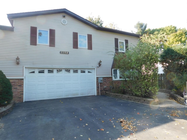 7702 N Gleneagle Dr, Kalamazoo, MI 49048 - rear view of house with brick siding, an attached garage, and asphalt driveway