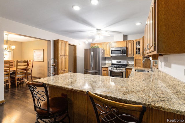 3349 Shimmons Rd, Auburn Hills, MI 48326 - kitchen with appliances with stainless steel finishes, a peninsula, a breakfast bar area, dark wood-style floors, and light stone counters