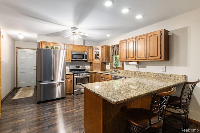3349 Shimmons Rd, Auburn Hills, MI 48326 - kitchen featuring appliances with stainless steel finishes, a peninsula, light stone countertops, brown cabinetry, and dark wood-style flooring