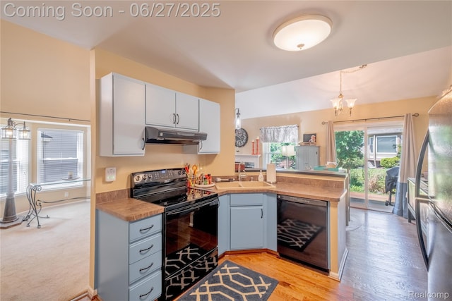 897 Whisperwood Trl, Fenton, MI 48430 - kitchen with black appliances, under cabinet range hood, a peninsula, white cabinets, and pendant lighting