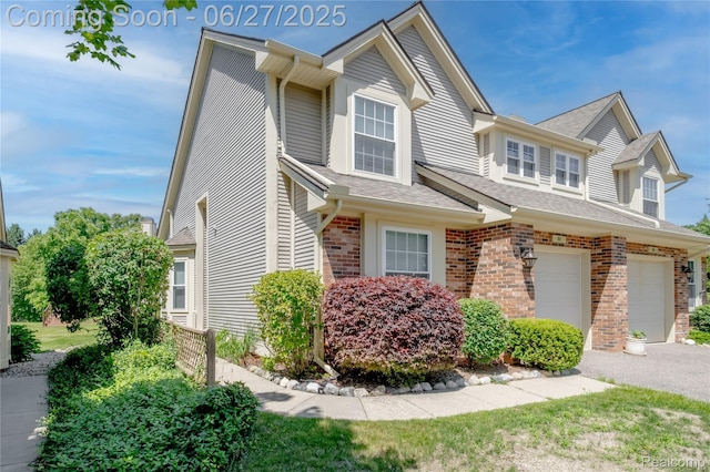 897 Whisperwood Trl, Fenton, MI 48430 - view of front of house with brick siding, a garage, a shingled roof, and driveway