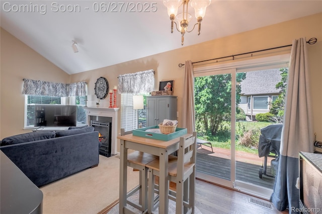 897 Whisperwood Trl, Fenton, MI 48430 - dining space with lofted ceiling, a chandelier, and a glass covered fireplace