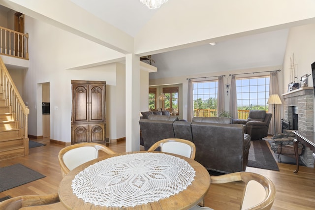 11713 Linderman Rd, Bear Lake, MI 49614 - dining area with wood finished floors, stairs, a brick fireplace, and high vaulted ceiling