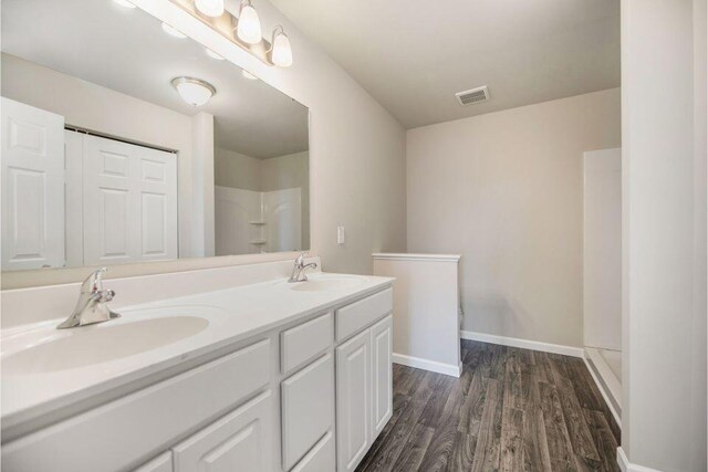 5680 Landrum Trl, Portage, MI 49024 - full bathroom featuring wood finished floors, double vanity, and a shower