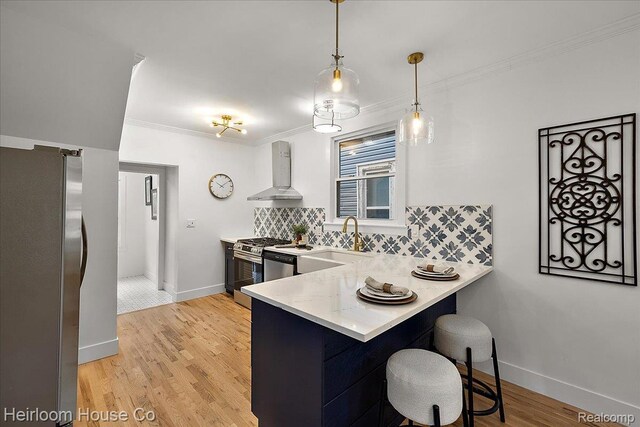 16514 Wildemere St, Detroit, MI 48221 - kitchen featuring wall chimney range hood, stainless steel appliances, tasteful backsplash, a peninsula, and crown molding