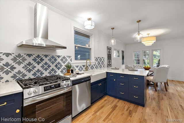 16514 Wildemere St, Detroit, MI 48221 - kitchen with appliances with stainless steel finishes, wall chimney exhaust hood, blue cabinets, a peninsula, and ornamental molding