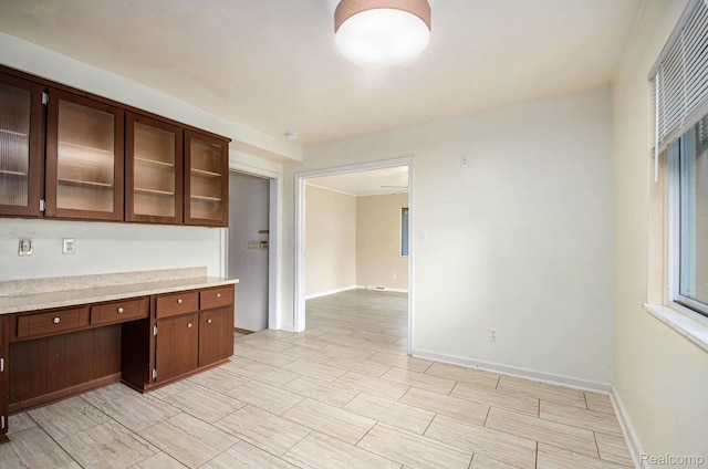 18319 Greenwald Dr, Southfield, MI 48075 - kitchen featuring light countertops, glass insert cabinets, dark brown cabinetry, and built in study area