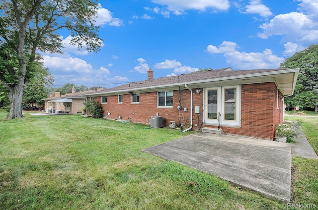 18319 Greenwald Dr, Southfield, MI 48075 - back of house with a chimney, brick siding, a lawn, and a patio