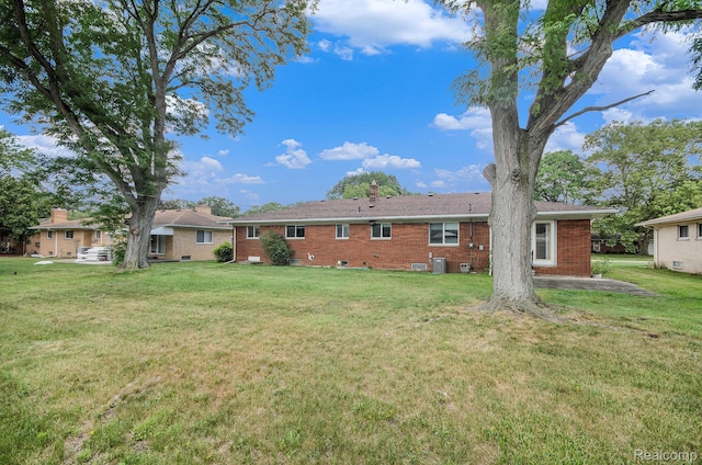 18319 Greenwald Dr, Southfield, MI 48075 - rear view of house with brick siding, a yard, and a chimney