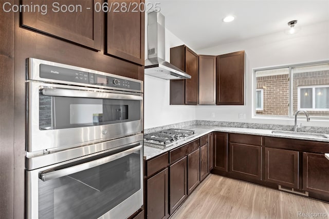 30493 Bradmore Rd, Warren, MI 48092 - kitchen with wall chimney exhaust hood, stainless steel appliances, dark brown cabinetry, light wood-style flooring, and light stone counters