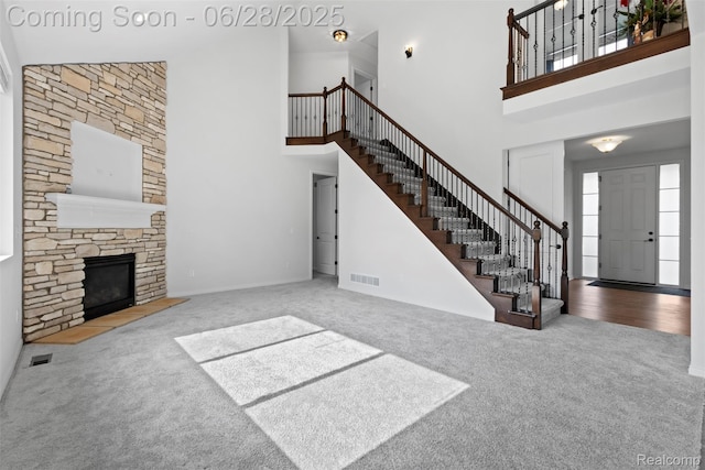 30493 Bradmore Rd, Warren, MI 48092 - unfurnished living room featuring carpet floors, a towering ceiling, stairway, a stone fireplace, and healthy amount of natural light