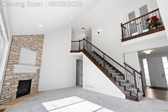 30493 Bradmore Rd, Warren, MI 48092 - unfurnished living room with high vaulted ceiling, stairs, carpet flooring, and a stone fireplace