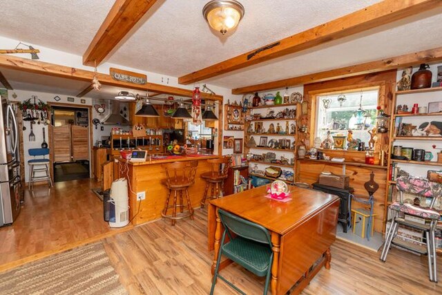 1213 Thomson Rd, Niles, MI 49120 - dining space featuring beamed ceiling, wood finished floors, a textured ceiling, and a bar