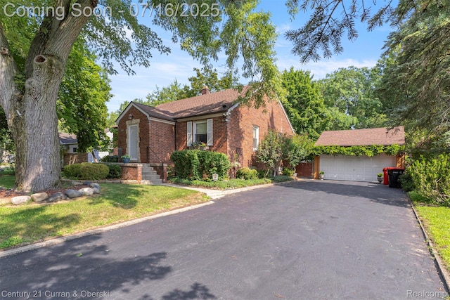 21280 Mada Ave, Southfield, MI 48075 - view of front of house with brick siding, a chimney, a garage, an outdoor structure, and asphalt driveway