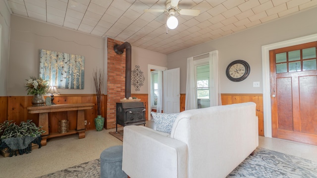 18216 S Schwark Rd, Three Oaks, MI 49128 - living area featuring a wainscoted wall, a wood stove, wooden walls, and ceiling fan