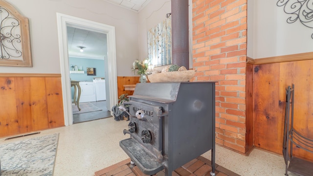 18216 S Schwark Rd, Three Oaks, MI 49128 - detailed view of wainscoting, washer and dryer, wooden walls, and a wood stove