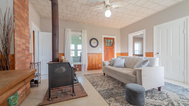 18216 S Schwark Rd, Three Oaks, MI 49128 - living room featuring a wainscoted wall, a wood stove, ceiling fan, and wood walls