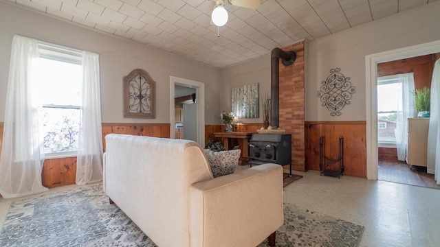 18216 S Schwark Rd, Three Oaks, MI 49128 - living area with a wainscoted wall, a wood stove, wood walls, and a ceiling fan